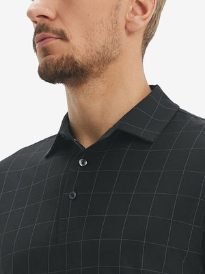 Front view from nose to chest of model wearing rich black grid  performance reflective checked collar golf shirt