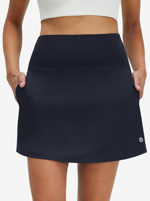 Front lower body shot of model wearing navy blue women's stretch a-line golf skort with 7 pockets