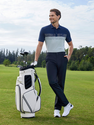Model leaning on a golf bag on course, stretch plain everyday pants in navy with clean style