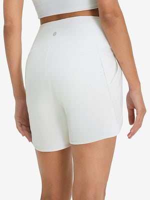 Back lower body shot of model wearing white women's high waist 2 in 1 quick dry shorts with 7 pockets