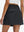 Back lower body shot of model wearing black women's stretch a-line golf skort with 7 pockets