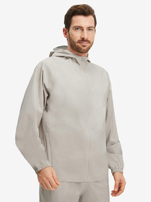 Front upper body shot of model wearing khaki grey waterproof lightweight rain jacket with hood