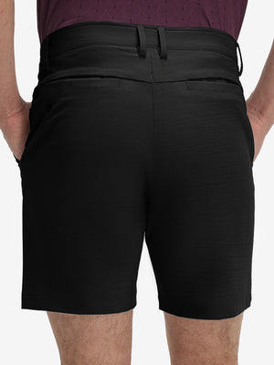 Back lower body shot of model wearing dark charcoal flat front hybrid golf shorts