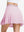 Back lower body shot of model wearing light pink women's moisture-wicking athletic tennis skirts