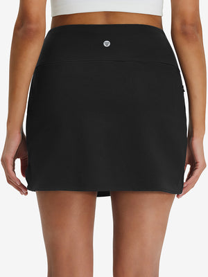 Back lower body shot of model wearing black high waist built-in short a-line golf skirt with 5 pockets