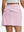 Back lower body shot of model wearing light pink women's stretch a-line golf skort with 7 pockets