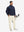 Model carrying a tennis bag, wearing beige lightweight flat front casual trousers in full-body view.