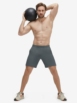 Front full body shot of model exercising in dark grey 4 way stretch breathable workout athletic shorts