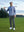 Model holding a golf club on course, wearing stretch plain everyday pants in dark grey