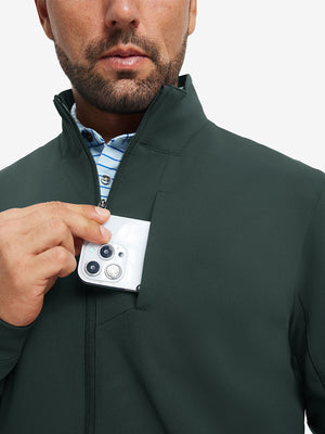 Close detail of hand in chest pocket of water-resistant zip up golf jacket in dark green.
