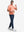 Front full body shot of model exercising in peach amber/calypso coral non-curl ribbed collar striped polo shirts