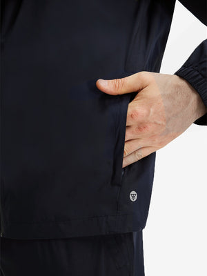 Detail view of outer pocket on navy waterproof lightweight rain jacket with hood