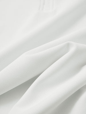 Close-up texture of white waffle texture 1/4 zip pullover fabric showing detailed waffle knit material and weave.