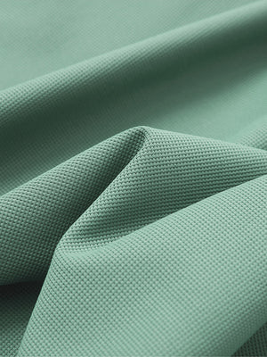 Close-up texture of green grey waffle texture 1/4 zip pullover fabric showing detailed waffle knit material and weave.