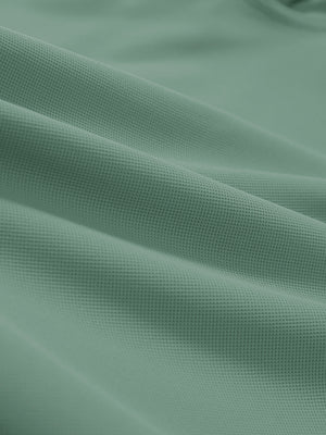 Close-up texture of green grey dry fit waffle textured collared golf shirts fabric showing weave detail.