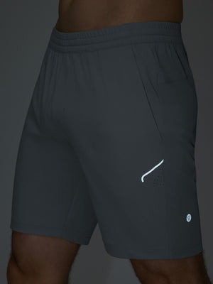 Detail of glow in the dark feature on dark grey 4 way stretch breathable workout athletic shorts
