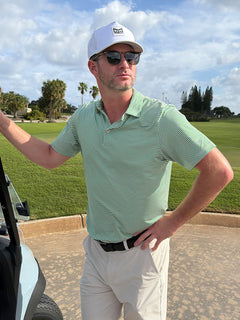 A model wearing a Cooling Stripe Golf Shirt stands with one hand on her hip