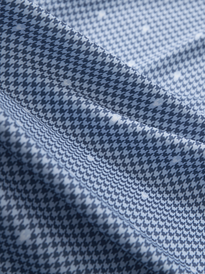 Close-up texture of light blue houndstooth stylish full print contrast collared golf polo shirts fabric showing weave detail.