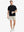 Detail shot with model holding a takeaway drink and sunglasses, featuring the BLACK polo’s side vent.