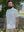 Model standing on grass with trees and house behind, wearing traditional breathable solid shirt in beige