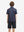 Back half-body view of youth wearing navy pink seagull performance print boys golf polo, showing rear design.