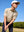 Model in pre-swing golf pose wearing beige ventilated pique performance polo